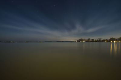 Scenic view of calm lake against sky at dusk