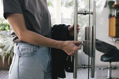 Midsection of female hair dresser opening lock of salon