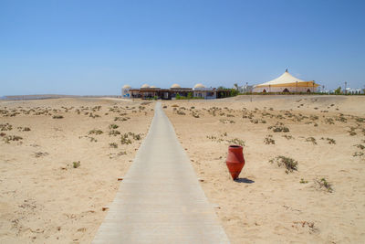 Lifeguard hut on sand at beach against clear blue sky