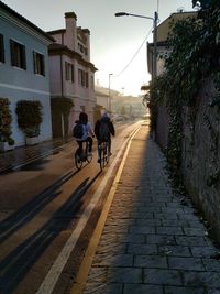 Rear view of men riding bicycles on street amidst buildings