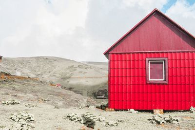 Red house on mountain against sky