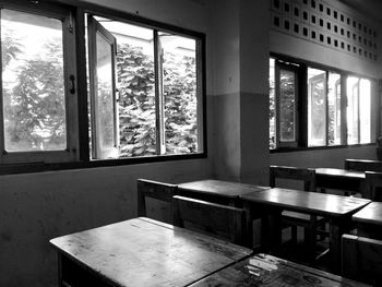 Empty benches and table by window