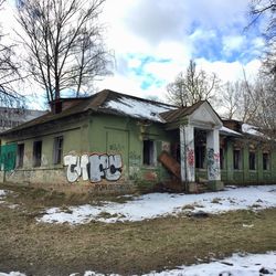 Graffiti on house by building against sky during winter