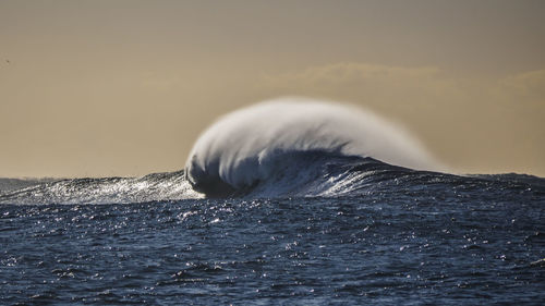 Idyllic view of splashing sea waves against sky