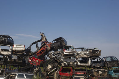 Low angle view of abandoned cars in junkyard against sky