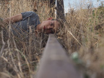 Portrait of young man lying on railroad track