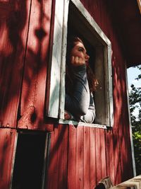 Low angle view of woman leaning on window