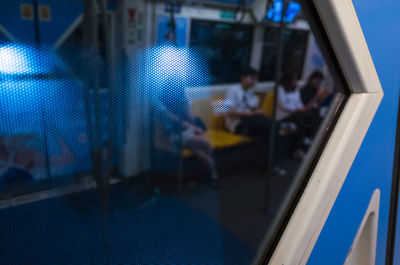 Reflection of man sitting on window at railroad station