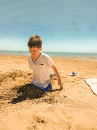 Rear view of boy on beach against sky