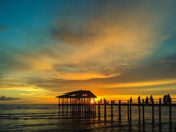 Silhouette lifeguard hut on beach against sky during sunset