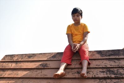Full length of boy standing on staircase against clear sky