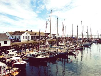 Boats moored at harbor against sky