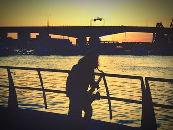 Silhouette man standing on bridge against sky during sunset