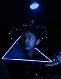 Close-up of young man looking away through illuminated triangle