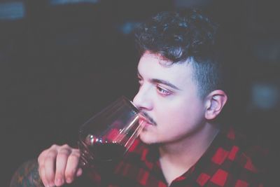 Close-up of man drinking red wine at night