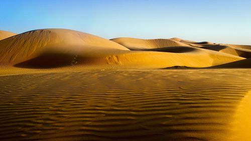 Sand dune in desert against clear sky