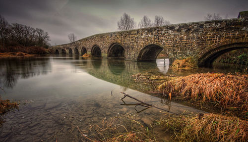 Arch bridge over river against sky