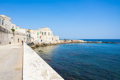 View of sea and buildings against clear blue sky