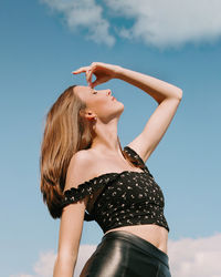 Midsection of woman with arms raised against sky