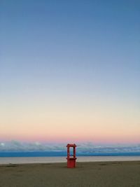 Empty bench on beach against clear sky