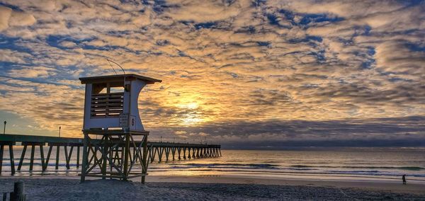 Lifeguard hut on beach against sky during sunset