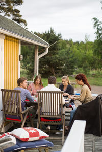 Group of friends sitting at dining table outside summer house