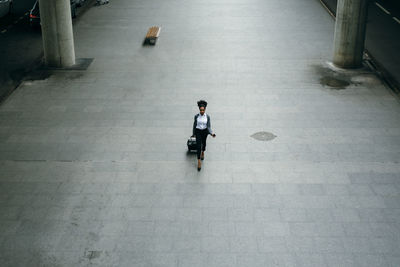 High angle view of woman pulling luggage while walking on street