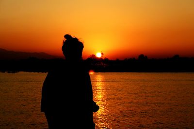 Silhouette man standing at beach against sky during sunset