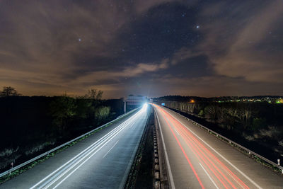 Light trails on highway against sky at night