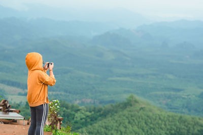 Woman tourist are using phone to take pictures of beautiful mountain scenery.