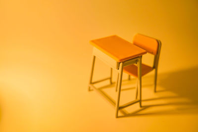 Empty chairs against yellow wall