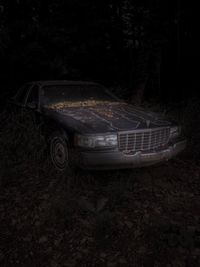 Abandoned car on field at night