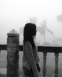 Rear view of girl standing on shore against sky