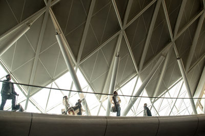 Low angle view of people standing on illuminated ceiling