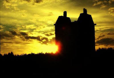 Silhouette of building against sunset sky