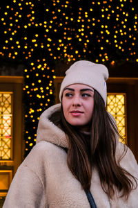 Young woman looking away while standing against christmas decoration
