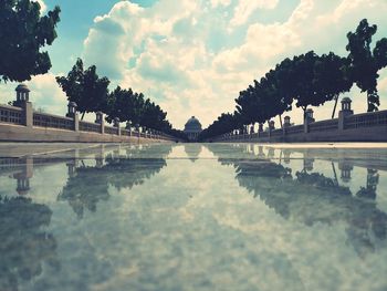 Reflection of trees in swimming pool against sky