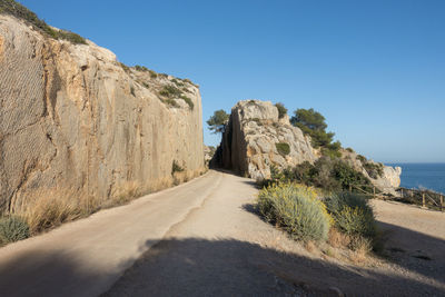 Road amidst rocks against clear blue sky