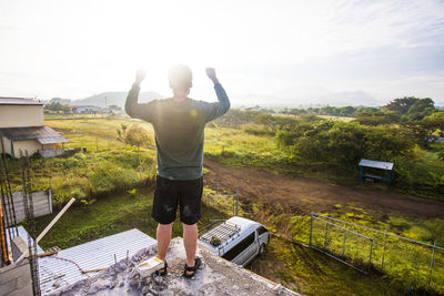 Man praising god from rooftop at sunrise.