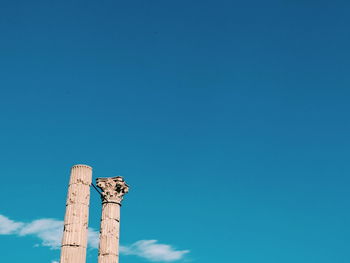 Low angle view of roman columns against blue sky