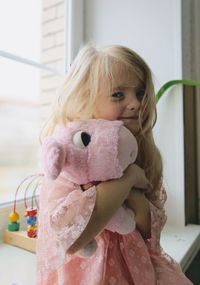 Portrait of cute girl holding stuffed toy at home