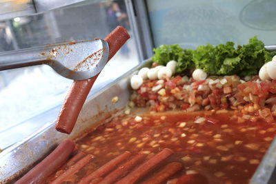 Close-up of tongs holding sausage