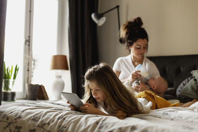 Woman using mobile phone while relaxing on bed at home