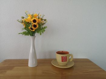 Close-up of vase on table against wall