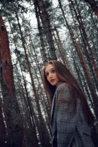 Low angle view of beautiful woman standing against tree in forest