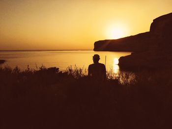 Silhouette people in sea at sunset