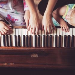 Cropped image of mother teaching daughters to play piano