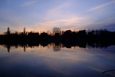 Silhouette trees by lake against sky during sunset