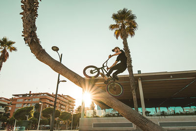 Low angle view of man with bicycle performing stunt against clear sky