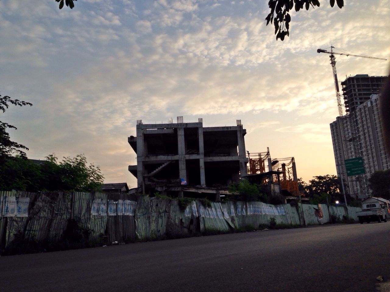 building exterior, architecture, built structure, sky, transportation, cloud - sky, street, road, cloudy, car, city, mode of transport, land vehicle, cloud, the way forward, building, street light, outdoors, low angle view, residential building